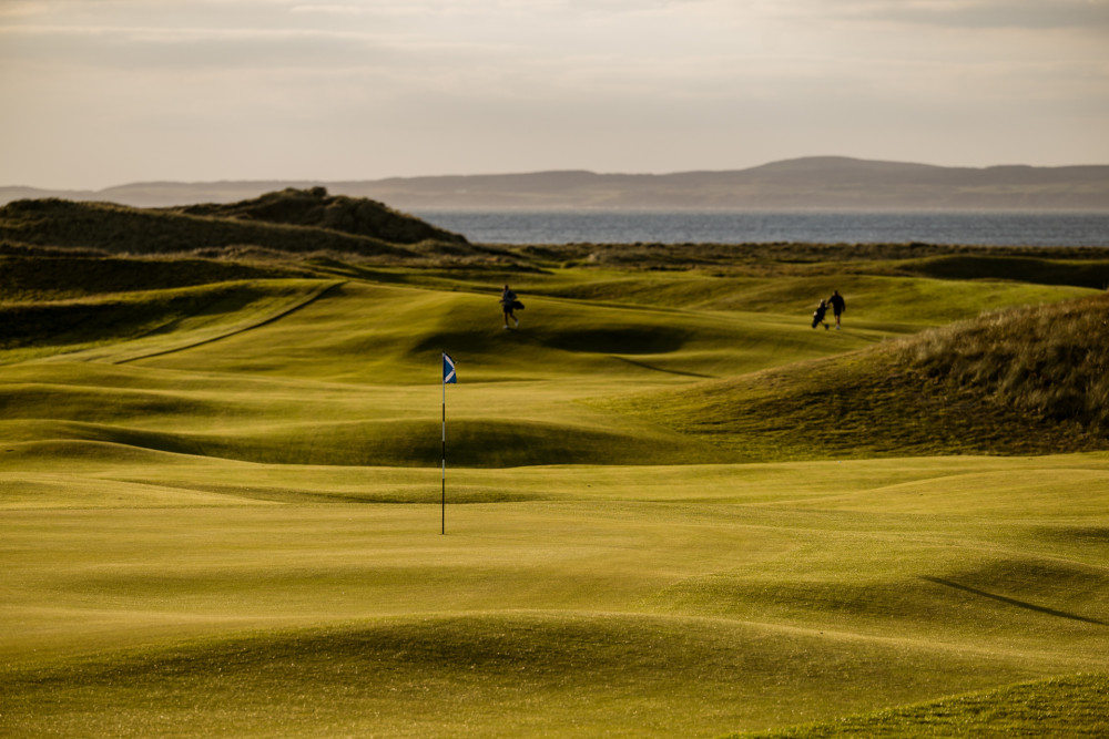 Two people playing on The Machrie course at sunset