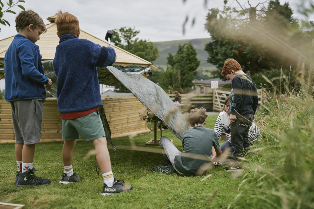 Children building a den during forest school at Another Place The Lake on Ullswater