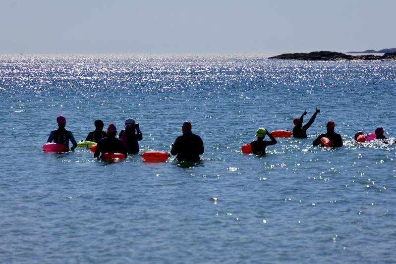 group of swimmer in wetsuits with floats swimming off the coast of Islay