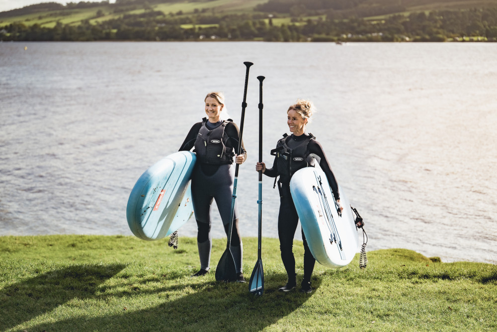 Two women stood with paddleboards