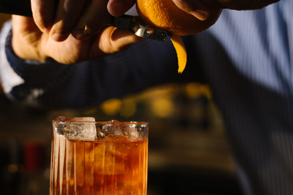 Bartender garnishing Lagavulin Boulevardier cocktail with orange peel